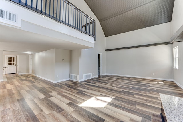 unfurnished living room featuring wood finished floors, high vaulted ceiling, baseboards, and visible vents