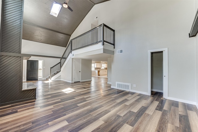 unfurnished living room featuring visible vents, baseboards, high vaulted ceiling, and stairs