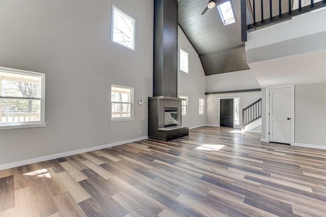 unfurnished living room featuring a high ceiling, wood finished floors, and a wealth of natural light