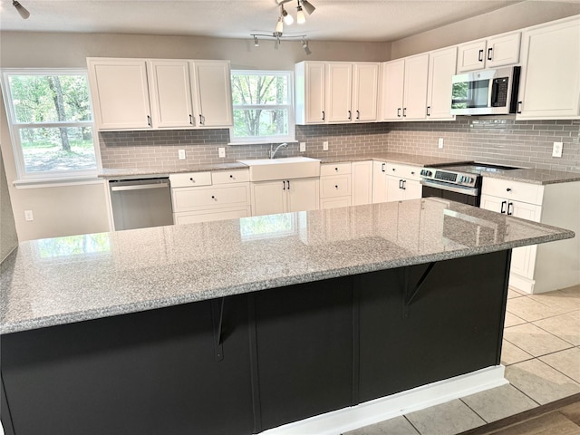 kitchen featuring a kitchen breakfast bar, a sink, light stone counters, and appliances with stainless steel finishes