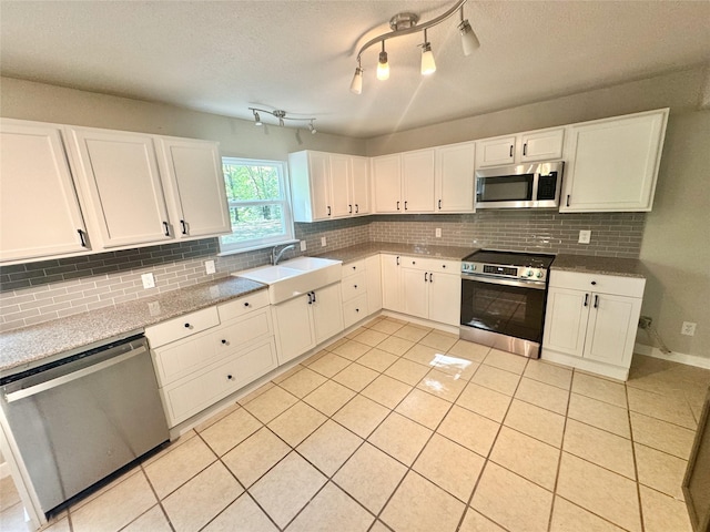 kitchen featuring decorative backsplash, white cabinetry, a sink, and appliances with stainless steel finishes