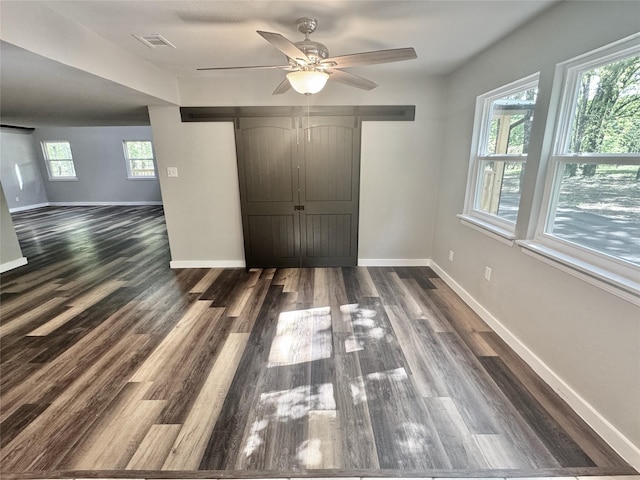 unfurnished bedroom featuring ceiling fan, baseboards, dark wood finished floors, and visible vents