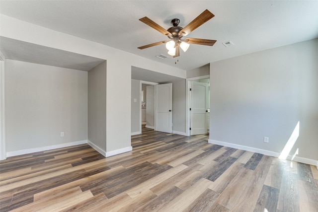 empty room featuring visible vents, baseboards, a ceiling fan, and wood finished floors