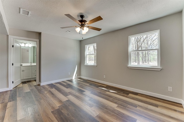 unfurnished bedroom with visible vents, baseboards, and dark wood-style floors