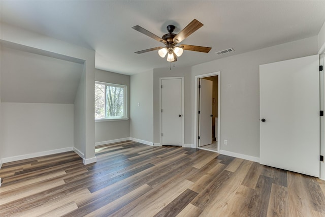 additional living space featuring wood finished floors, ceiling fan, baseboards, and visible vents