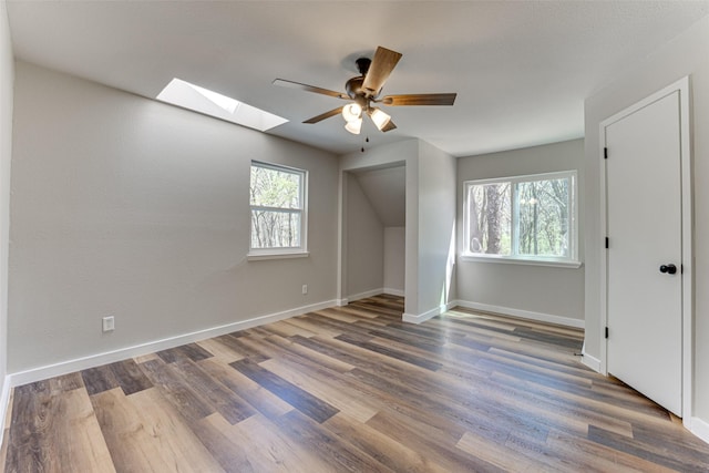 bonus room with a skylight, wood finished floors, ceiling fan, and baseboards