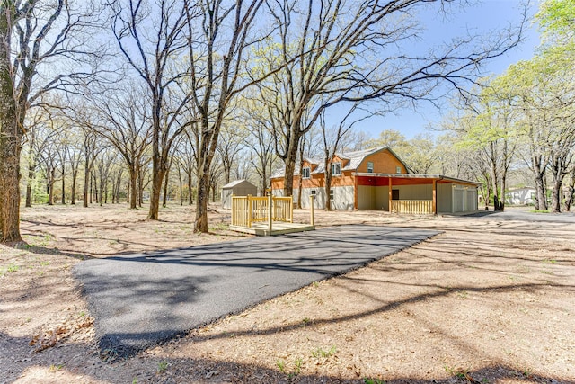 view of front of house featuring an outbuilding, driveway, and a deck