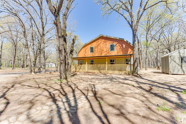view of property exterior featuring an outbuilding, a porch, and a gambrel roof