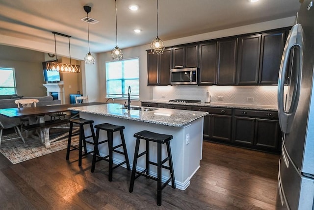 201 Virginia Ln, Hickory Creek, TX 75065 - kitchen featuring stainless steel appliances, light stone counters, dark wood-style flooring, recessed lighting, and a kitchen bar