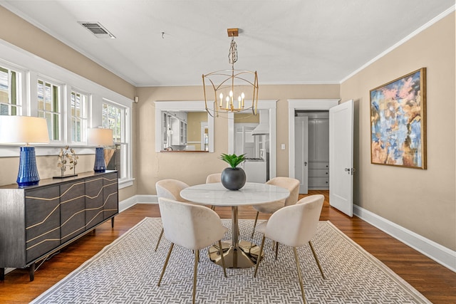 dining area featuring ornamental molding, dark wood-type flooring, baseboards, a chandelier, and visible vents