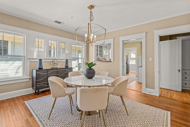 dining space with an inviting chandelier, wood-type flooring, baseboards, and visible vents
