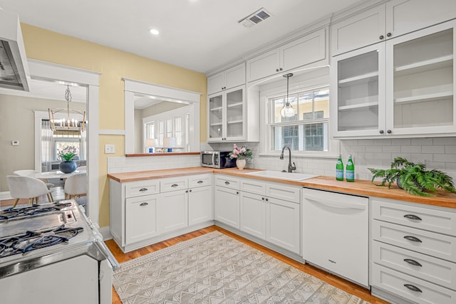 kitchen featuring white appliances, visible vents, butcher block countertops, and a sink