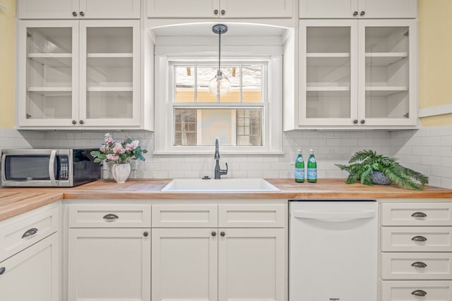 kitchen with stainless steel microwave, a sink, wood counters, dishwasher, and white cabinets