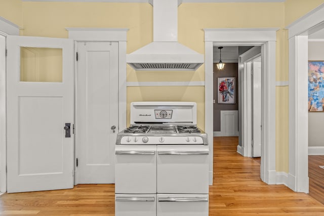kitchen with baseboards, light wood-type flooring, custom exhaust hood, and range with two ovens