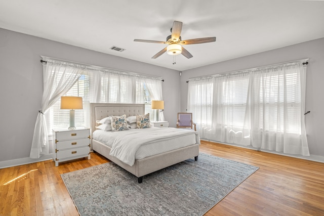 bedroom featuring a ceiling fan, wood finished floors, baseboards, and visible vents