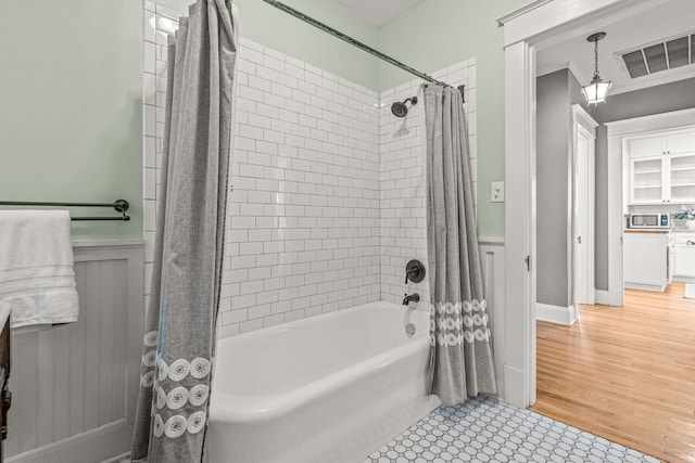 full bathroom featuring wainscoting, visible vents, ornamental molding, and shower / bath combo