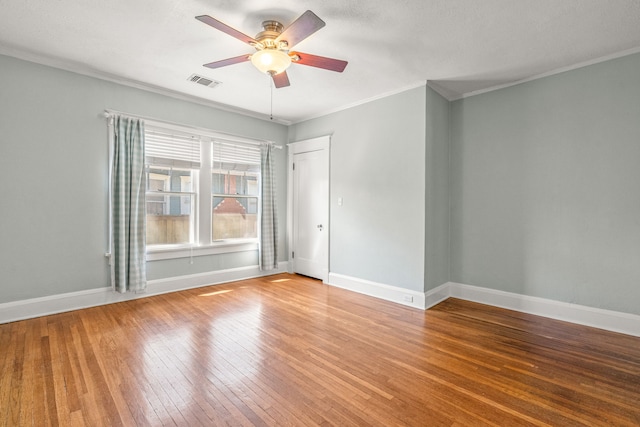 unfurnished room featuring hardwood / wood-style floors, baseboards, visible vents, and crown molding
