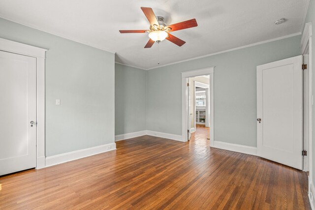 empty room featuring baseboards, crown molding, a ceiling fan, and hardwood / wood-style flooring