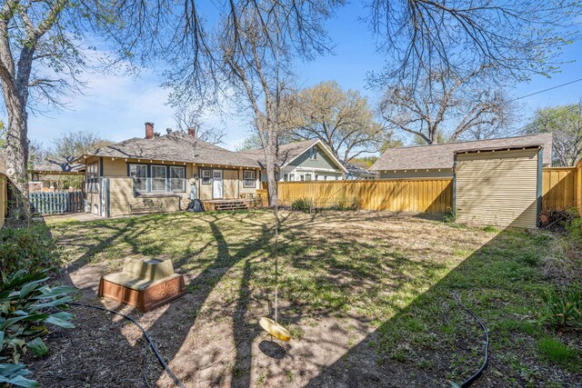 view of yard featuring a fenced backyard, a shed, and an outbuilding