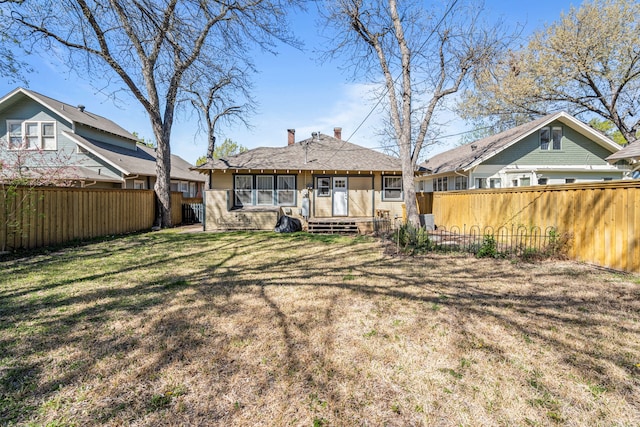 back of house featuring a lawn, a chimney, and a fenced backyard
