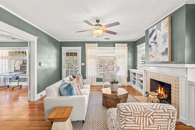 living area with a ceiling fan, ornamental molding, and wood finished floors