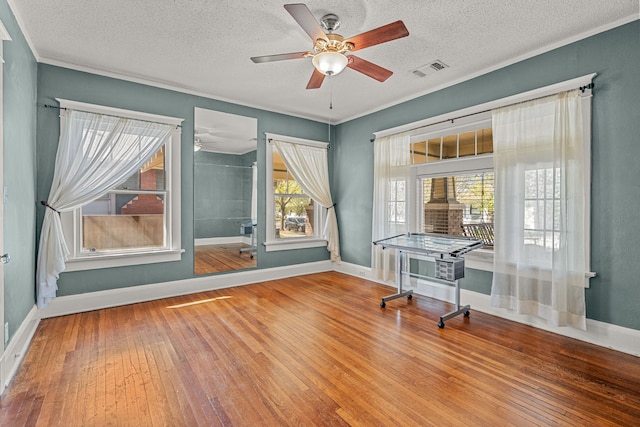 home office featuring baseboards, visible vents, ceiling fan, ornamental molding, and hardwood / wood-style floors