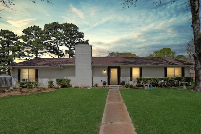 ranch-style home featuring brick siding, a chimney, and a front lawn