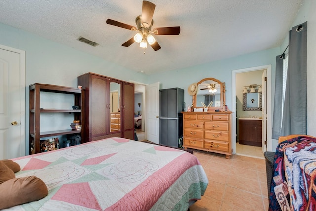 bedroom featuring ceiling fan, a textured ceiling, ensuite bath, visible vents, and light tile patterned flooring