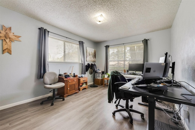 home office with a textured ceiling, light wood finished floors, and baseboards