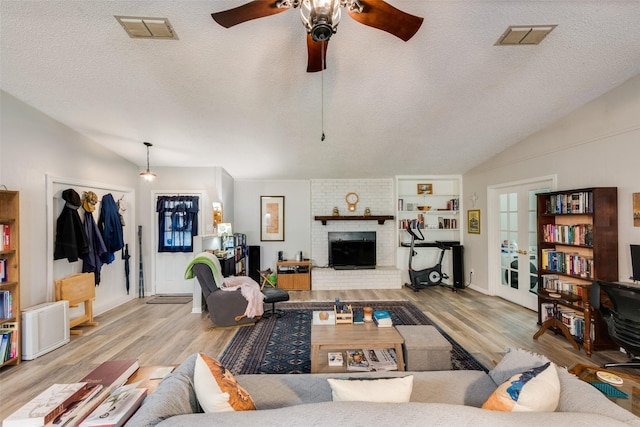 living area with a ceiling fan, wood finished floors, vaulted ceiling, and visible vents