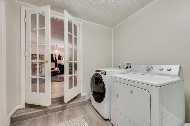clothes washing area with laundry area, light wood-style flooring, a textured ceiling, separate washer and dryer, and french doors