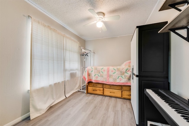 bedroom with light wood-style flooring, a textured ceiling, a ceiling fan, and ornamental molding