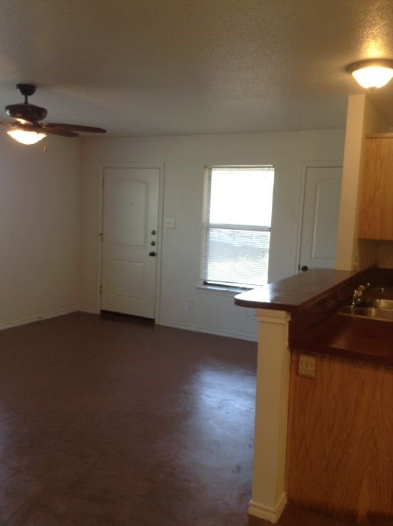 8124 Doreen Ave, Fort Worth, TX 76116 - kitchen featuring baseboards, a sink, dark countertops, a ceiling fan, and a peninsula