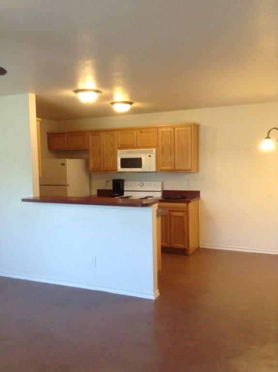 8124 Doreen Ave, Fort Worth, TX 76116 - kitchen with white appliances, dark countertops, baseboards, and a peninsula