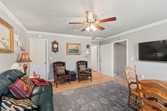 living room with visible vents, a ceiling fan, wood finished floors, and ornamental molding