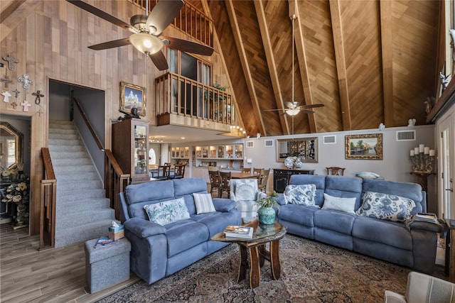 living area with high vaulted ceiling, a ceiling fan, stairs, and visible vents