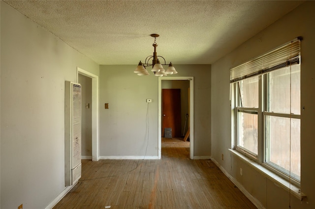 210AND218 N Collins, Colbert, OK 74733 - unfurnished dining area with an inviting chandelier, hardwood / wood-style floors, a heating unit, baseboards, and a textured ceiling