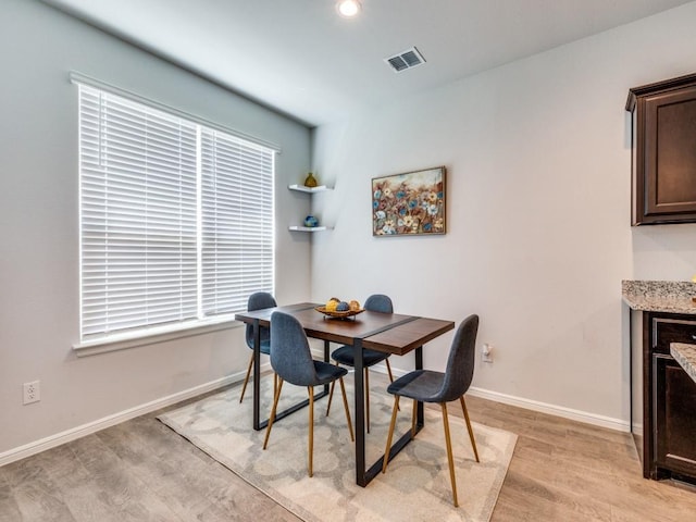 dining space featuring baseboards, light wood finished floors, and visible vents