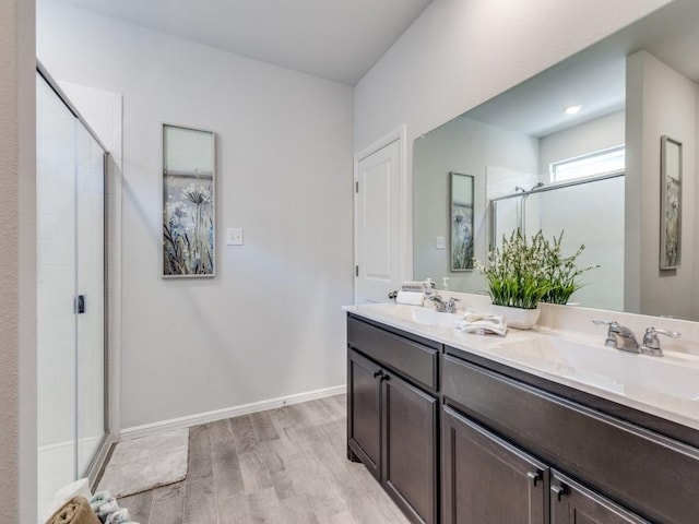 bathroom with a shower stall, baseboards, wood finished floors, and a sink