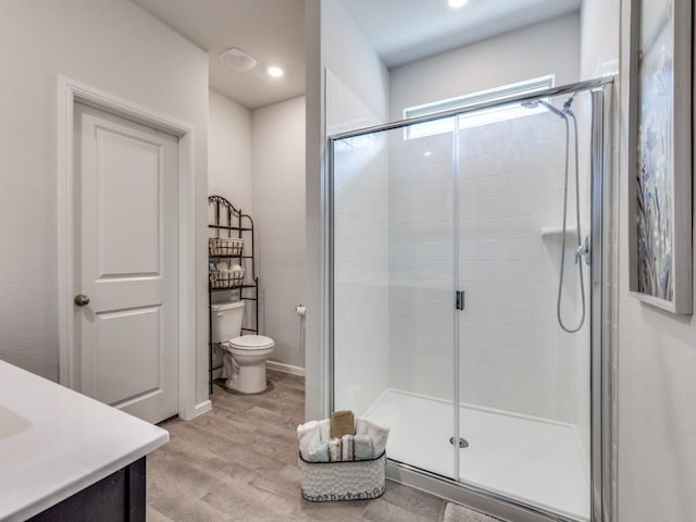 bathroom with toilet, a stall shower, recessed lighting, and wood finished floors