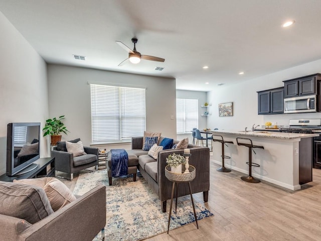 living room with a ceiling fan, visible vents, recessed lighting, and light wood-type flooring