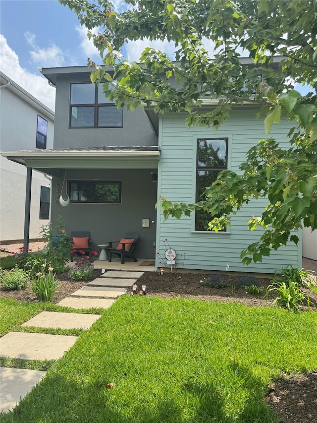 view of front of house featuring stucco siding, a porch, and a front lawn
