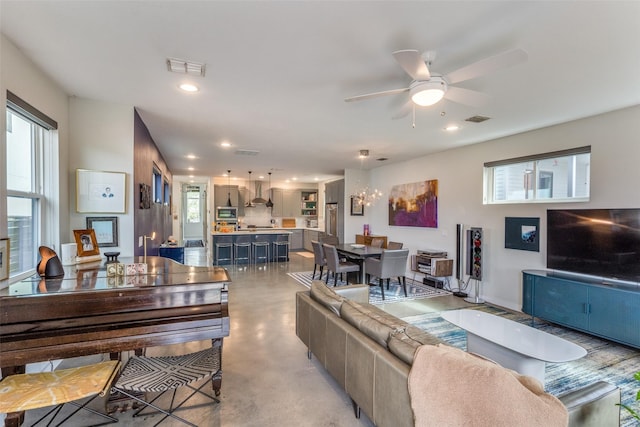 living room featuring visible vents, concrete flooring, ceiling fan, and plenty of natural light