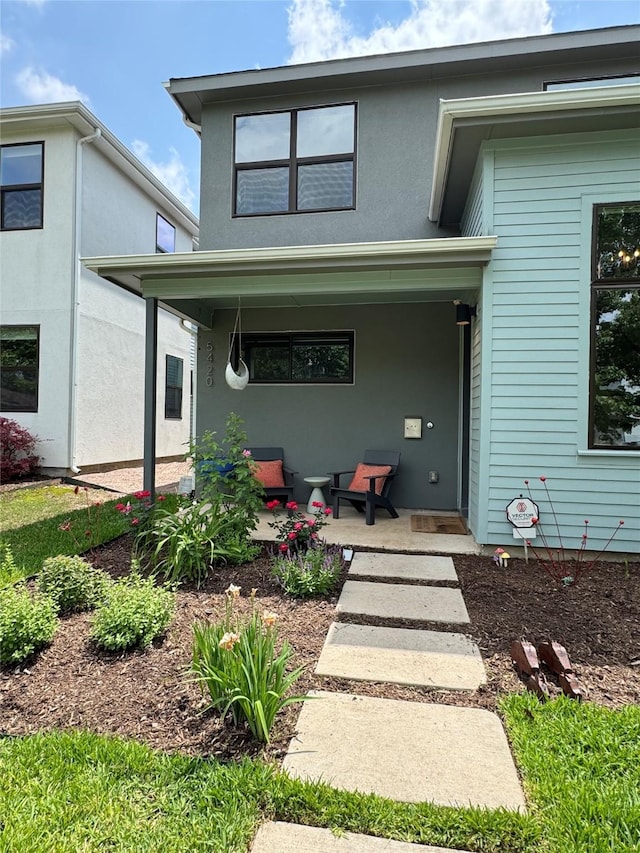 back of house with a porch and stucco siding