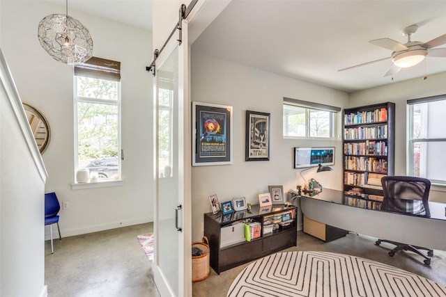 office area with baseboards, a barn door, ceiling fan, and concrete flooring
