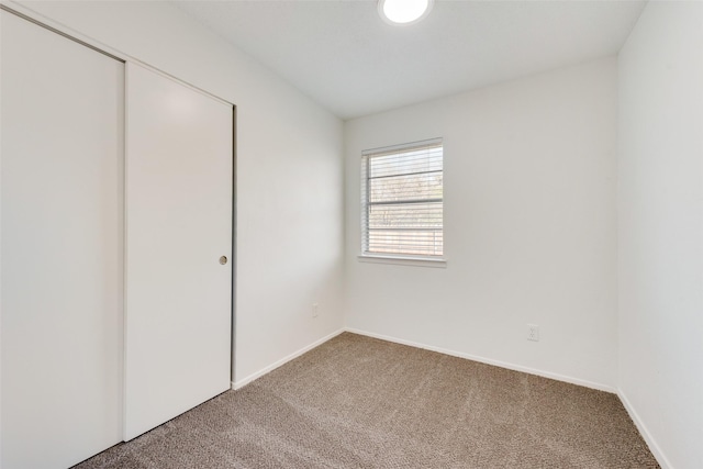 unfurnished bedroom with baseboards, a closet, and carpet flooring