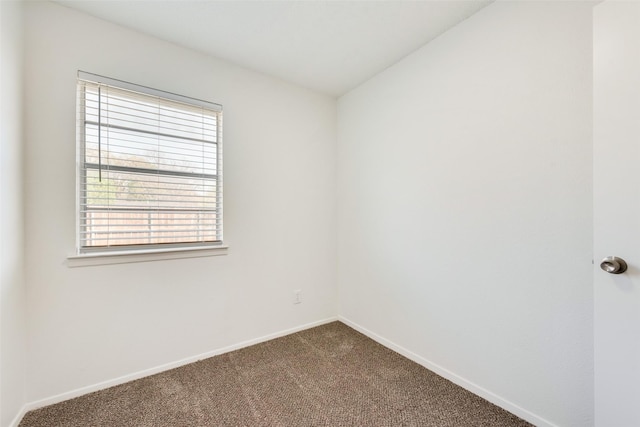 unfurnished room with baseboards, dark colored carpet, and plenty of natural light