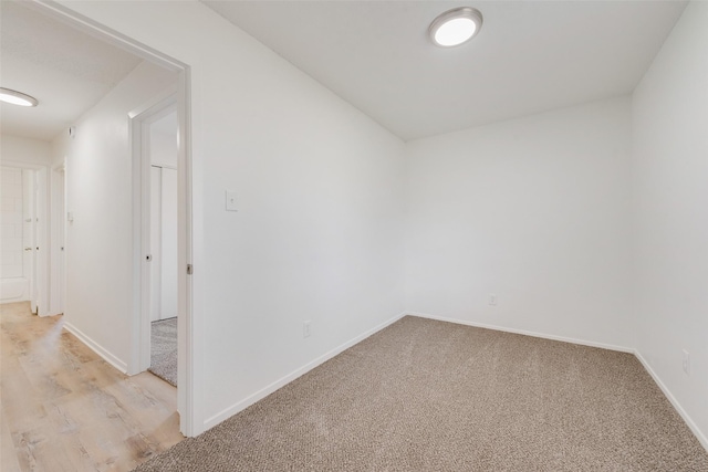 unfurnished room with baseboards and light colored carpet