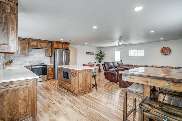 kitchen featuring open floor plan, a sink, stainless steel appliances, and light wood finished floors