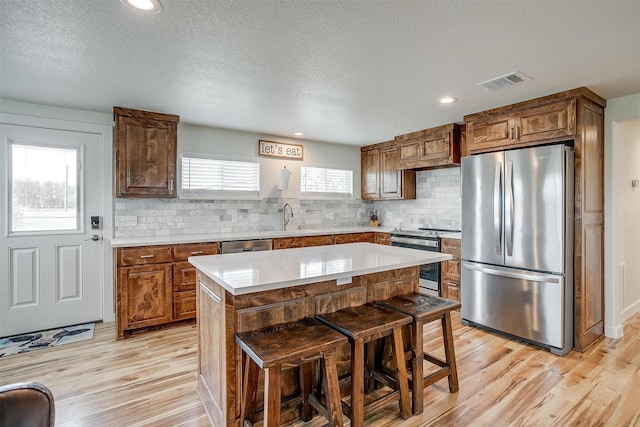 kitchen with a sink, visible vents, stainless steel appliances, and light wood finished floors